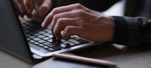 Osoba kuca na laptopu.